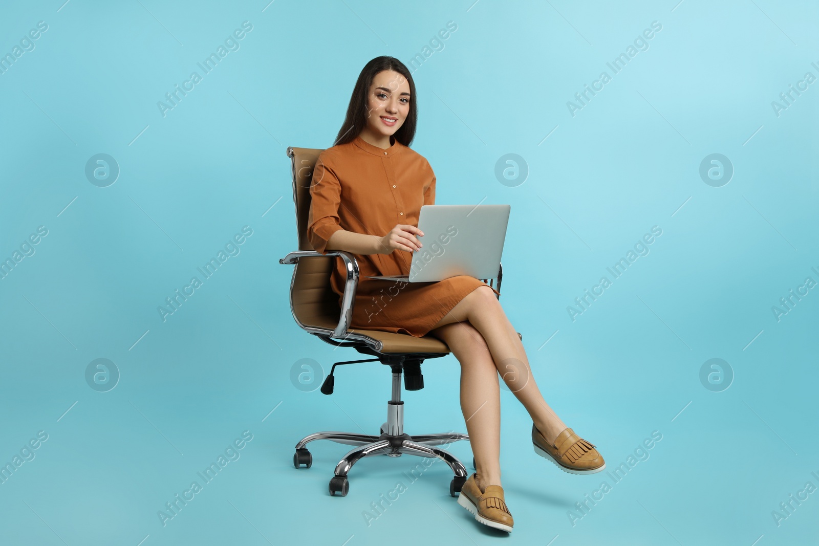 Photo of Young woman with laptop sitting in comfortable office chair on turquoise background