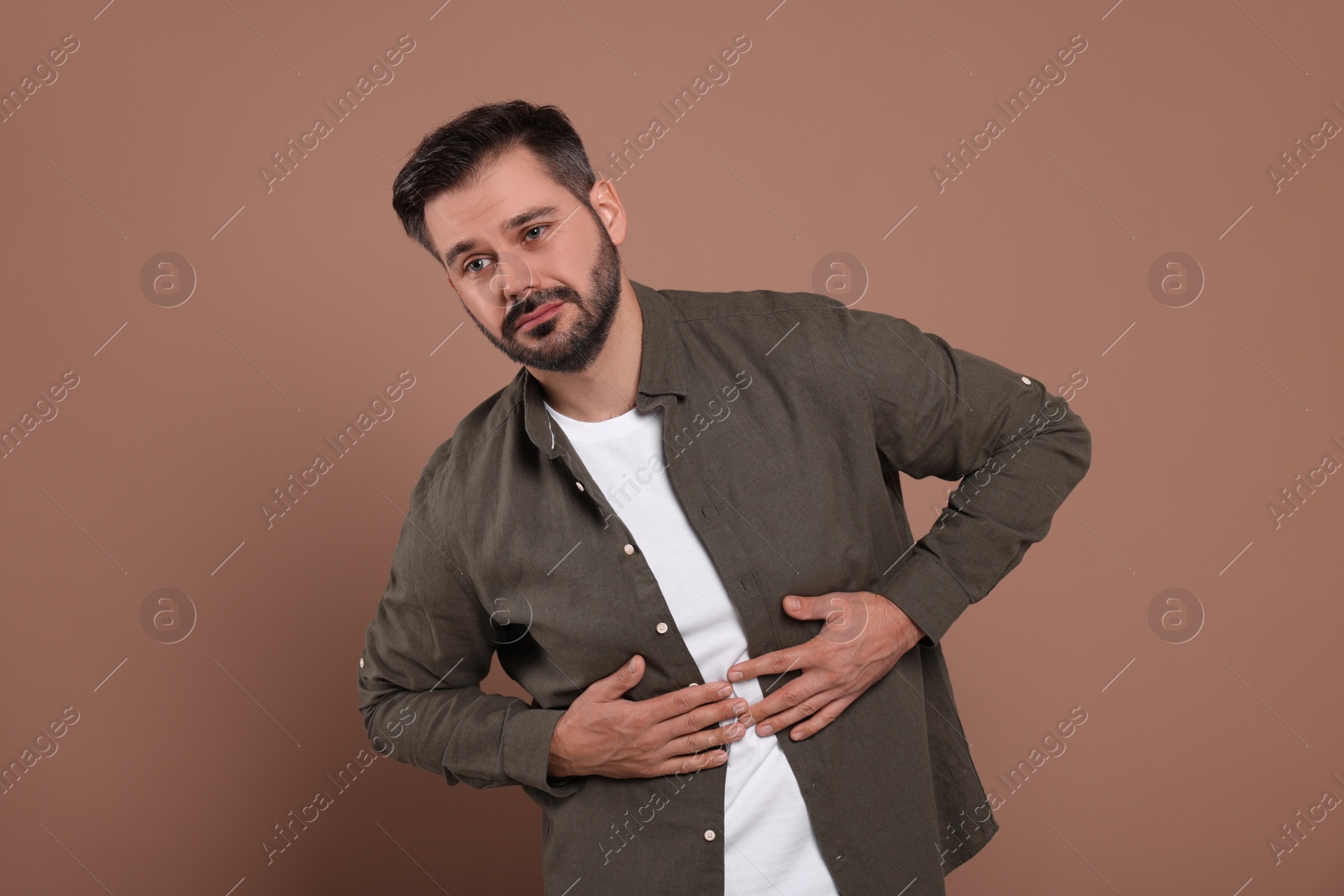 Photo of Man suffering from stomach pain on light brown background