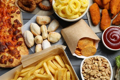French fries, chips other fast food on gray wooden table, flat lay