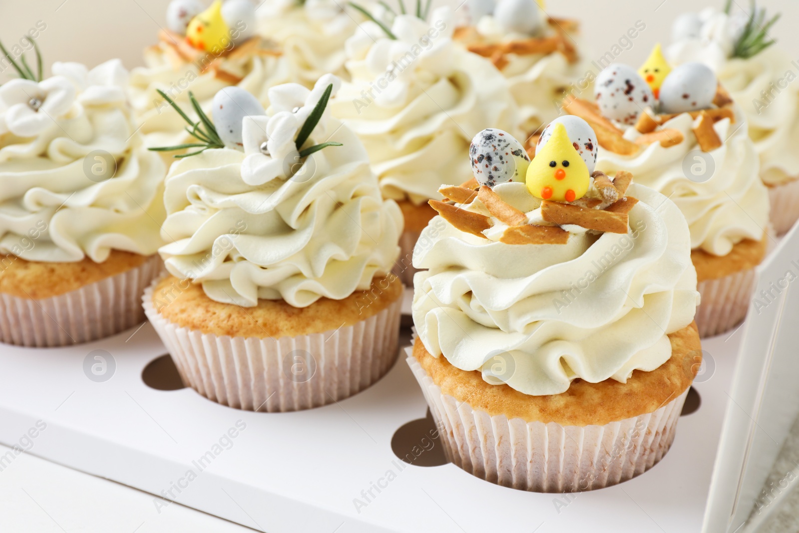 Photo of Tasty Easter cupcakes with vanilla cream in box, closeup