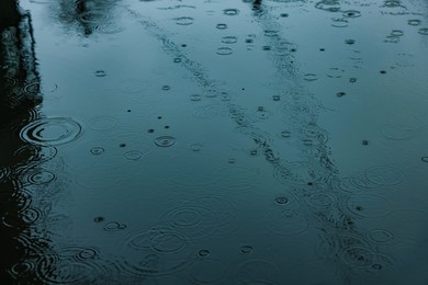 Photo of Rain drops falling down onto puddle outdoors, above view