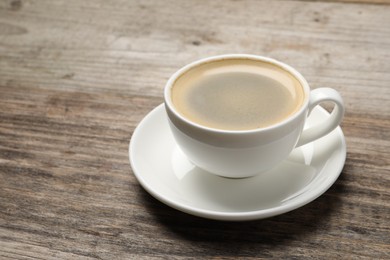 Aromatic coffee in cup on wooden table. Space for text