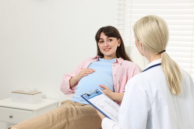 Happy pregnant woman having doctor appointment in hospital. Space for text
