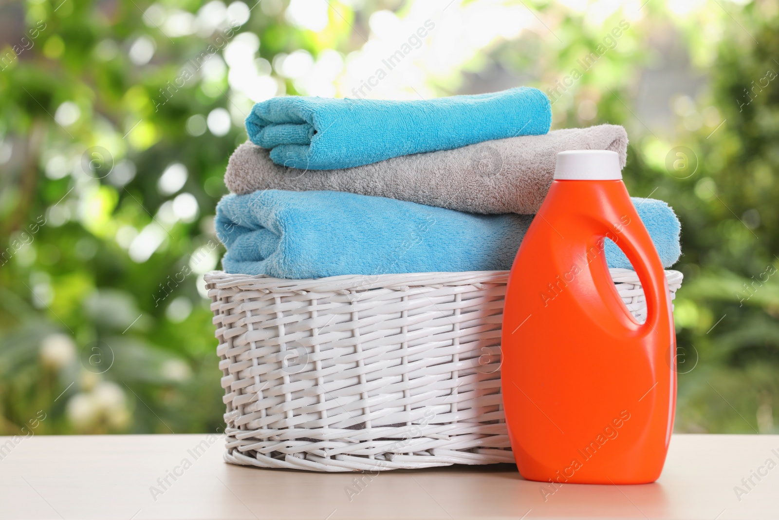 Photo of Soft bath towels and laundry detergent on table against blurred background