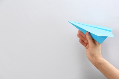 Woman holding paper plane on white background, closeup. Space for text