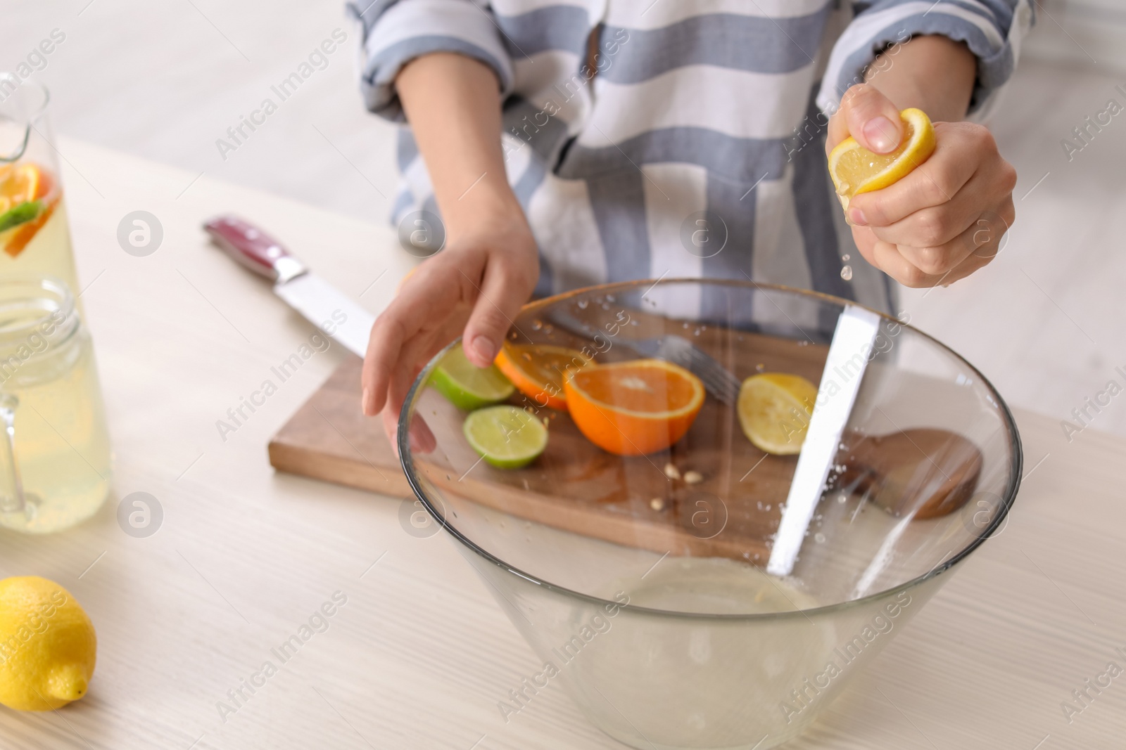 Photo of Young woman squeezing juice in bowl for lemonade on table, closeup. Natural detox drink