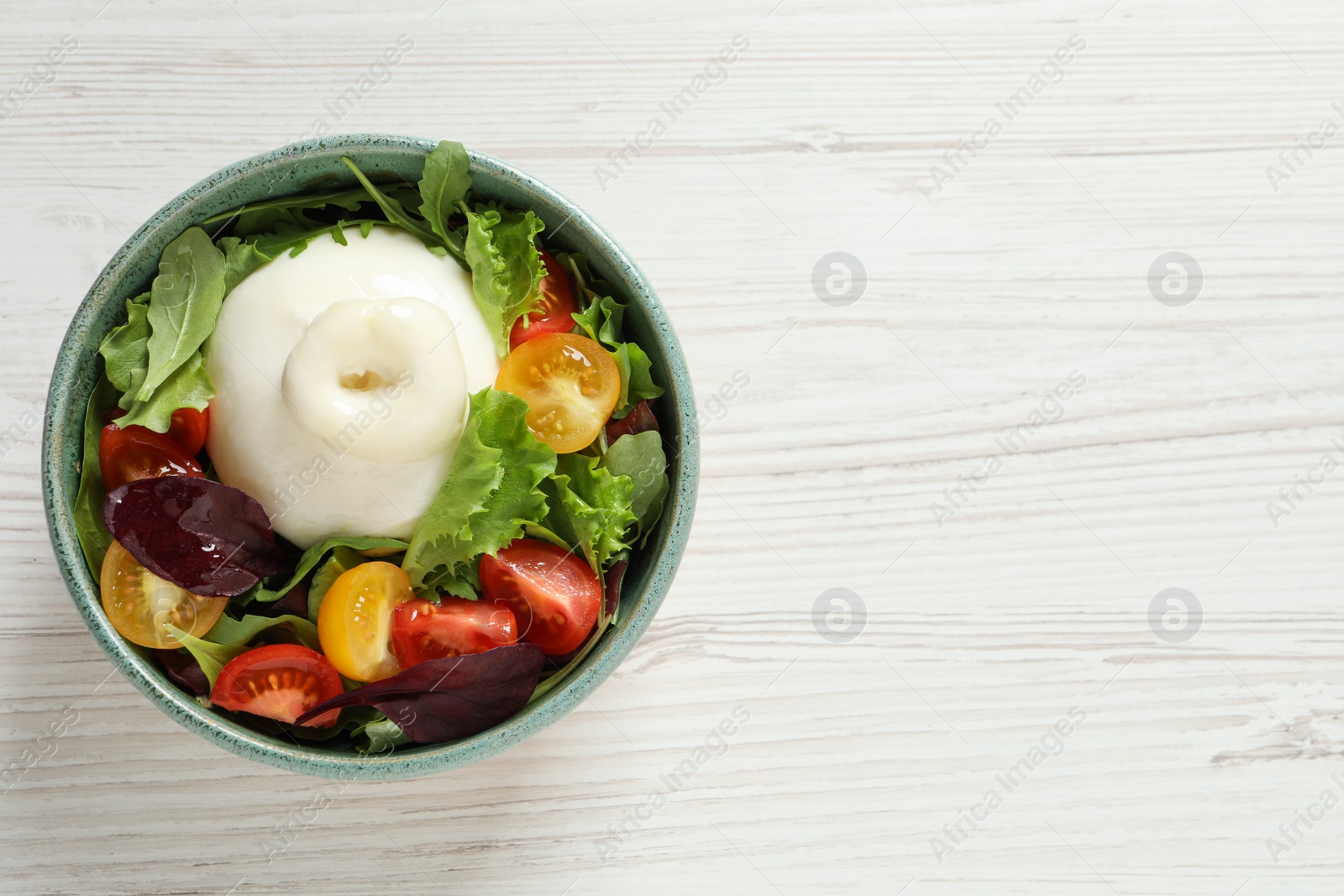 Photo of Delicious burrata salad with colorful cherry tomatoes and arugula on white wooden table, top view. Space for text