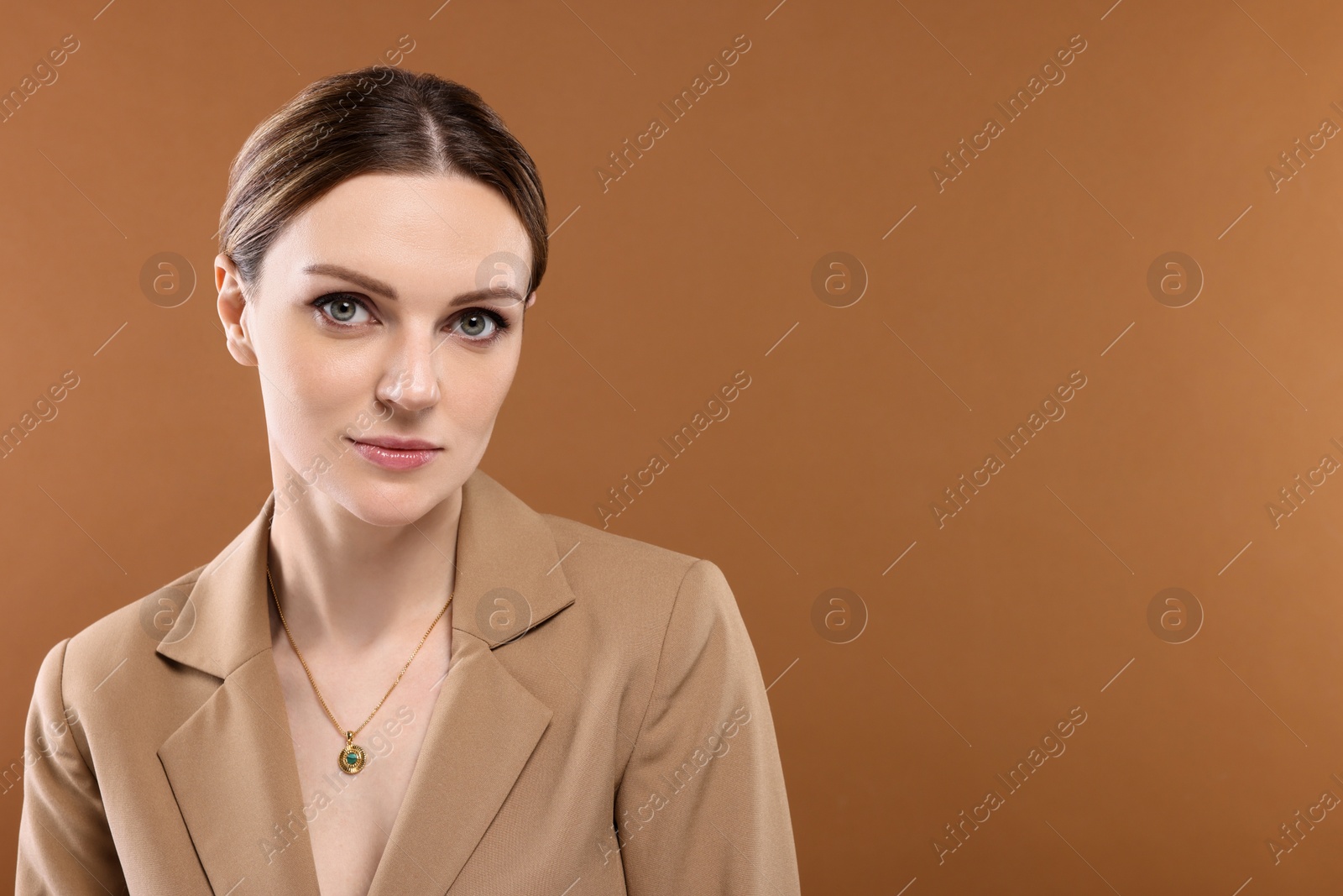 Photo of Beautiful woman with elegant necklace on brown background. Space for text