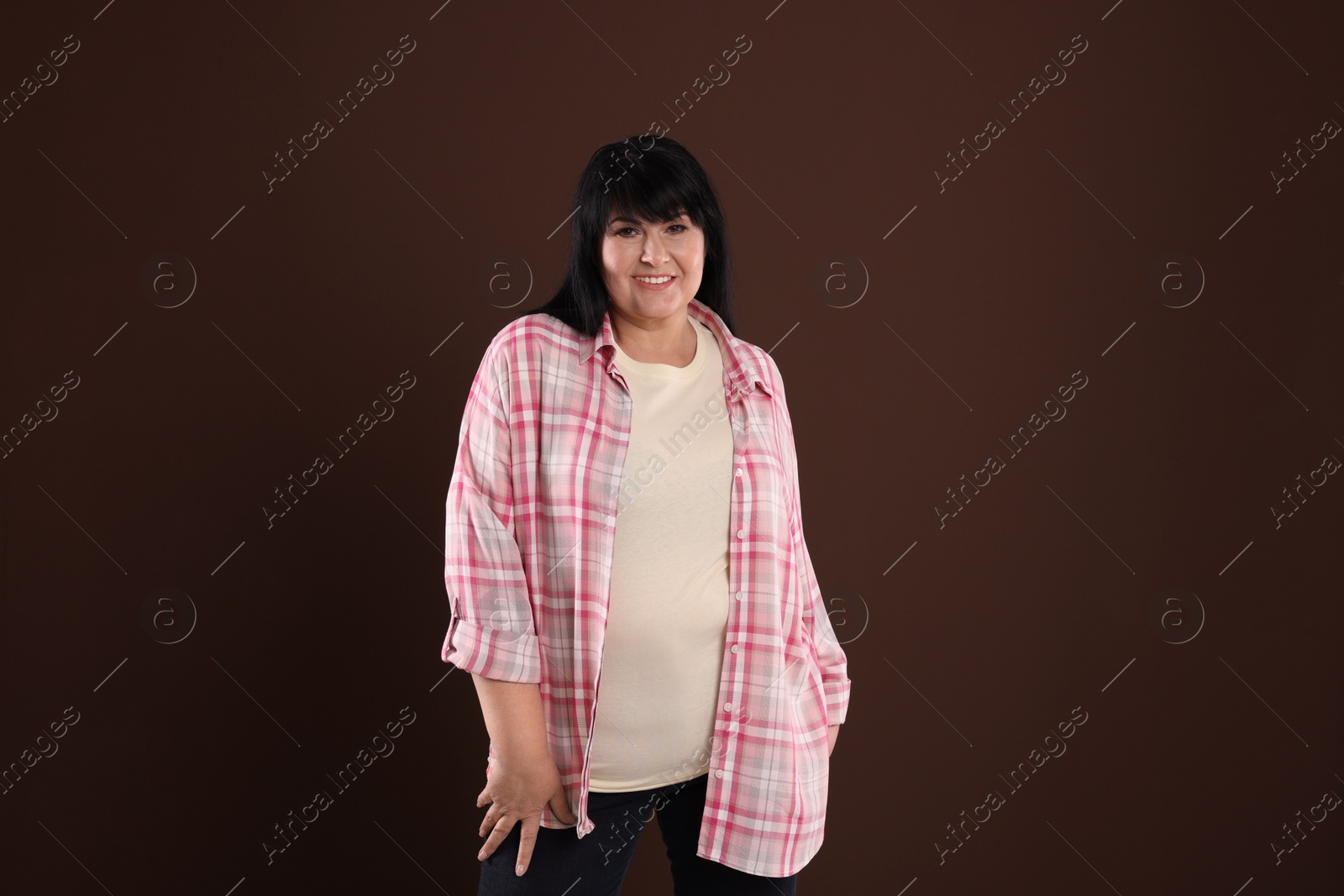 Photo of Beautiful overweight mature woman with charming smile on brown background