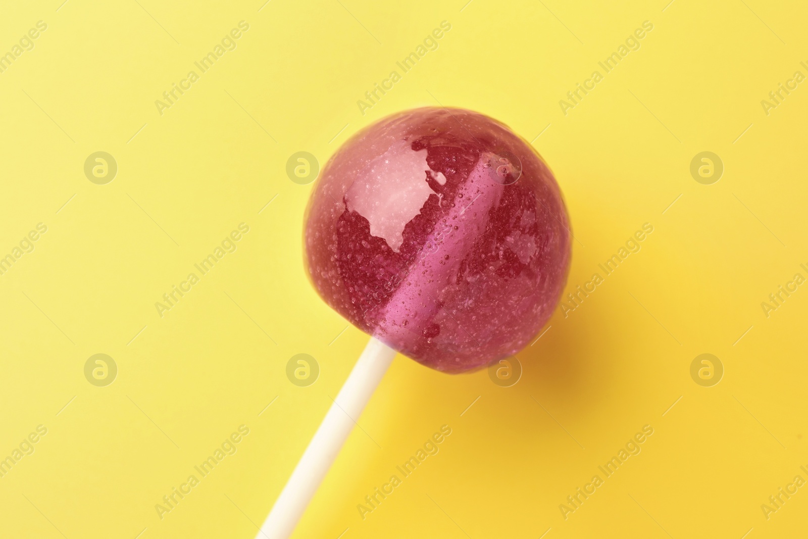 Photo of One tasty lollipop on yellow background, closeup