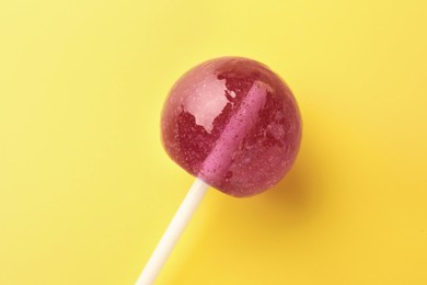 Photo of One tasty lollipop on yellow background, closeup