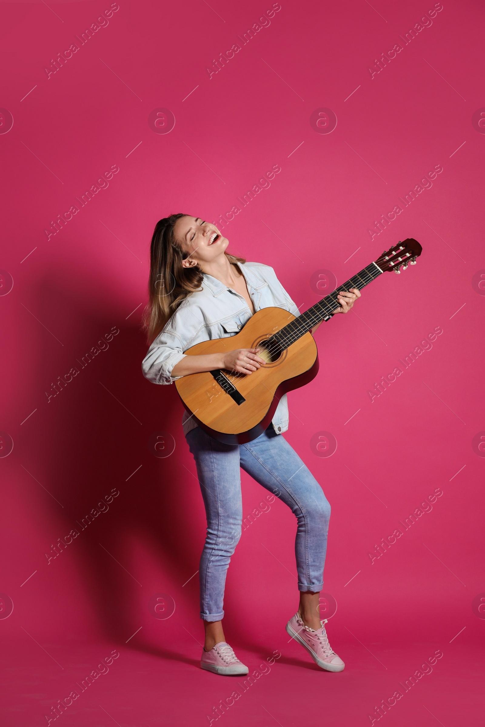 Photo of Young woman playing acoustic guitar on color background