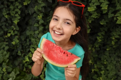 Photo of Cute little girl with watermelon outdoors on sunny day
