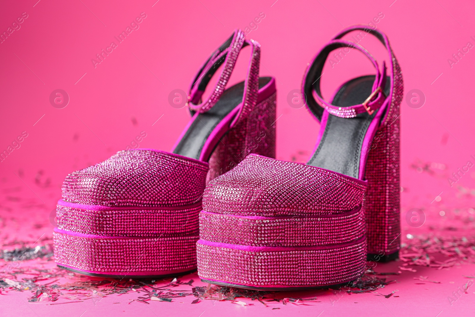 Photo of Fashionable punk square toe ankle strap pumps and confetti on pink background. Shiny party platform high heeled shoes