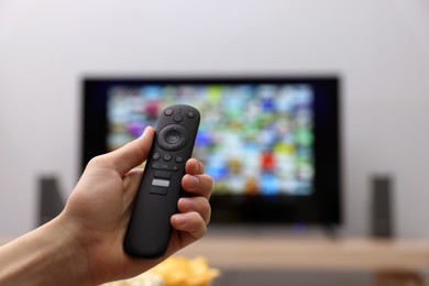 Photo of Woman switching channels on TV set with remote control at home, closeup. Space for text