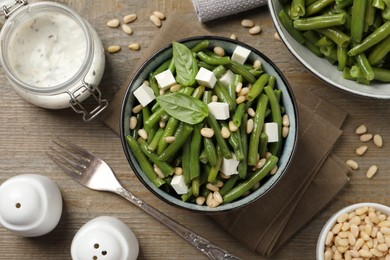 Photo of Delicious salad with green beans, pine nuts and cheese served on wooden table, flat lay