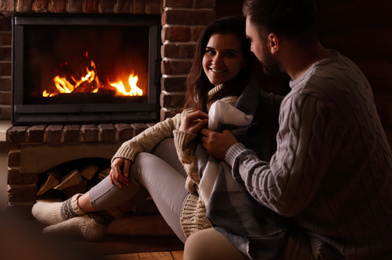 Photo of Lovely couple sitting on floor near fireplace at home. Winter vacation