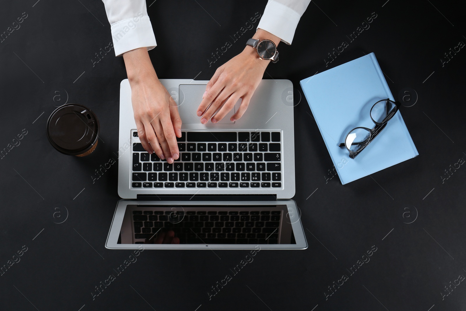 Photo of Young woman using laptop on black background, top view