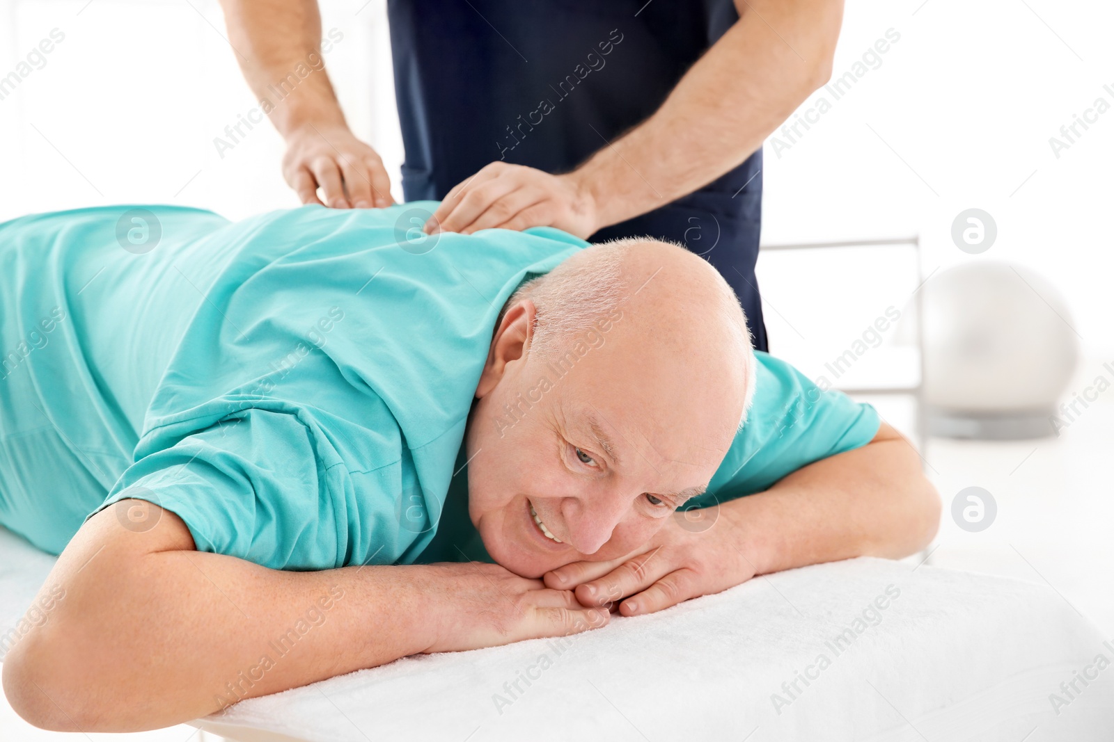 Photo of Young physiotherapist working with senior patient in clinic