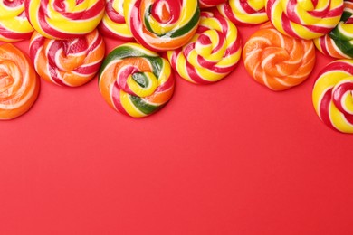 Photo of Sweet lollipops on red background, flat lay. Space for text