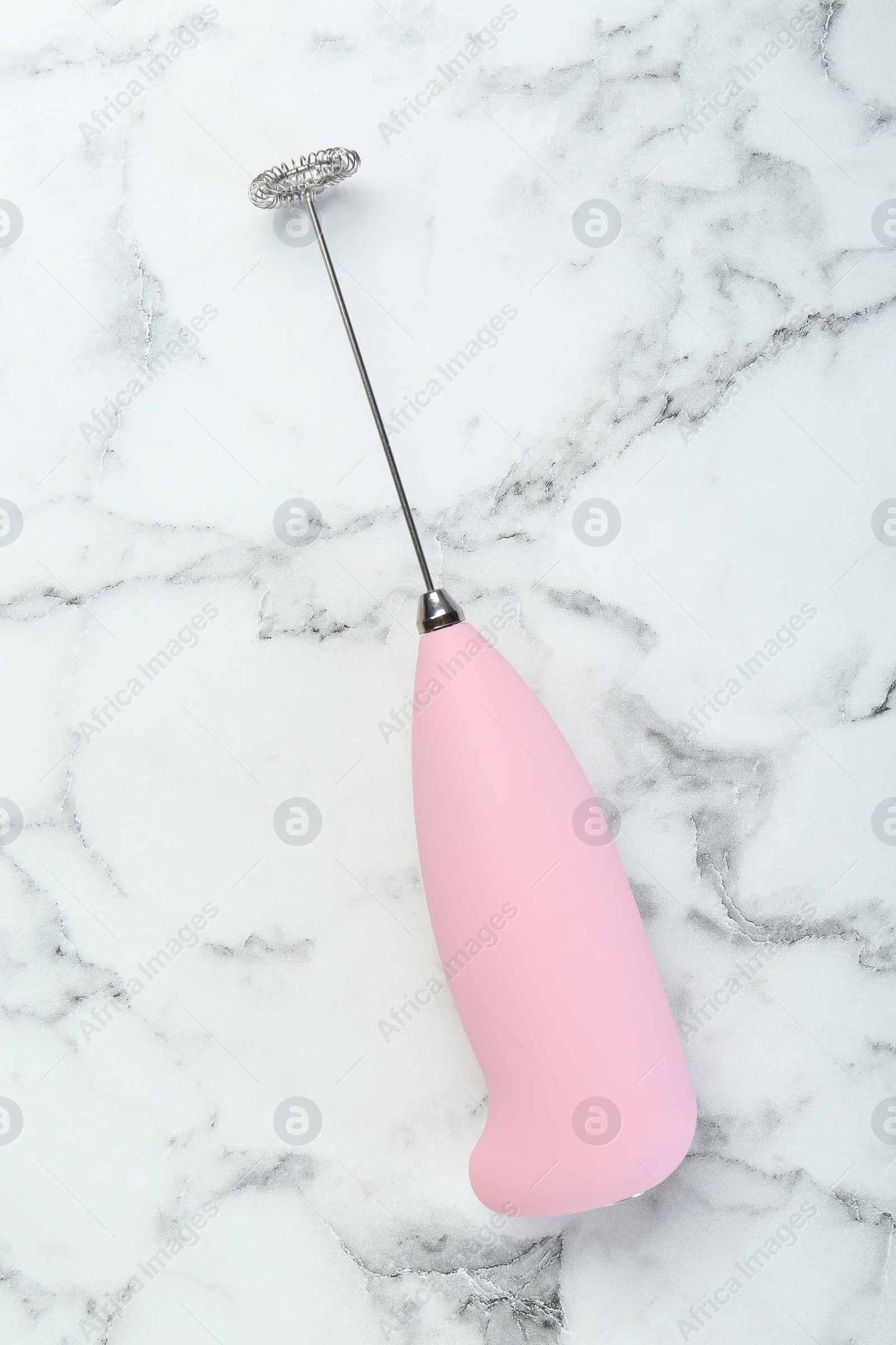 Photo of Pink milk frother wand on white marble table, top view