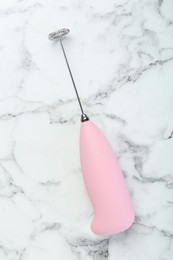 Pink milk frother wand on white marble table, top view