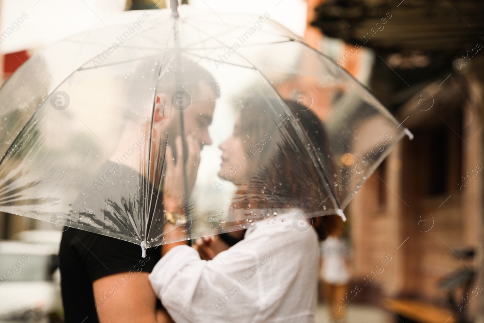 Photo of Young couple with umbrella enjoying time together under rain on city street