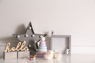Different baby accessories and toys on white table in child room. Interior design