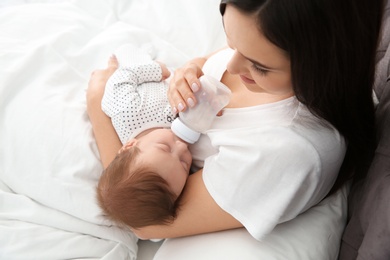 Photo of Woman feeding her baby from bottle on bed
