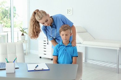 Female medical assistant examining child in clinic