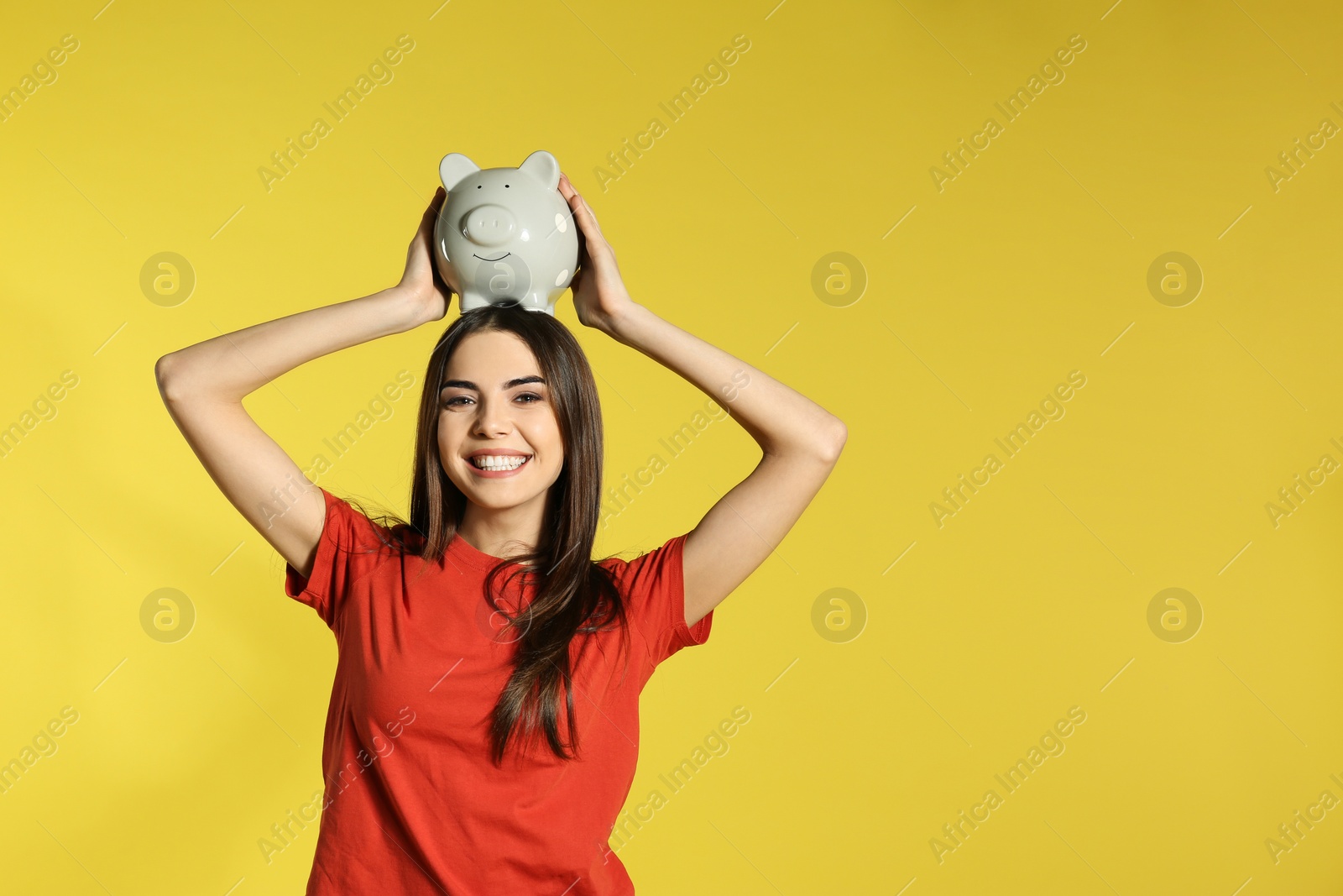 Photo of Young woman with piggy bank on color background, space for text. Money saving