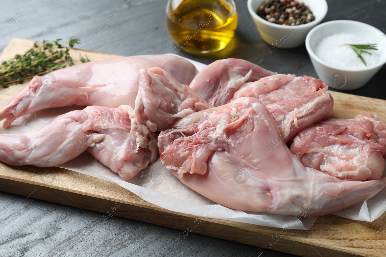 Photo of Fresh raw rabbit legs on black table, closeup