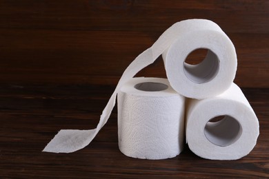 Photo of Many soft toilet paper rolls on wooden table, closeup. Space for text