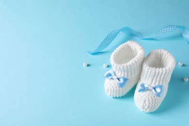 Photo of Handmade baby booties on color background. Space for text