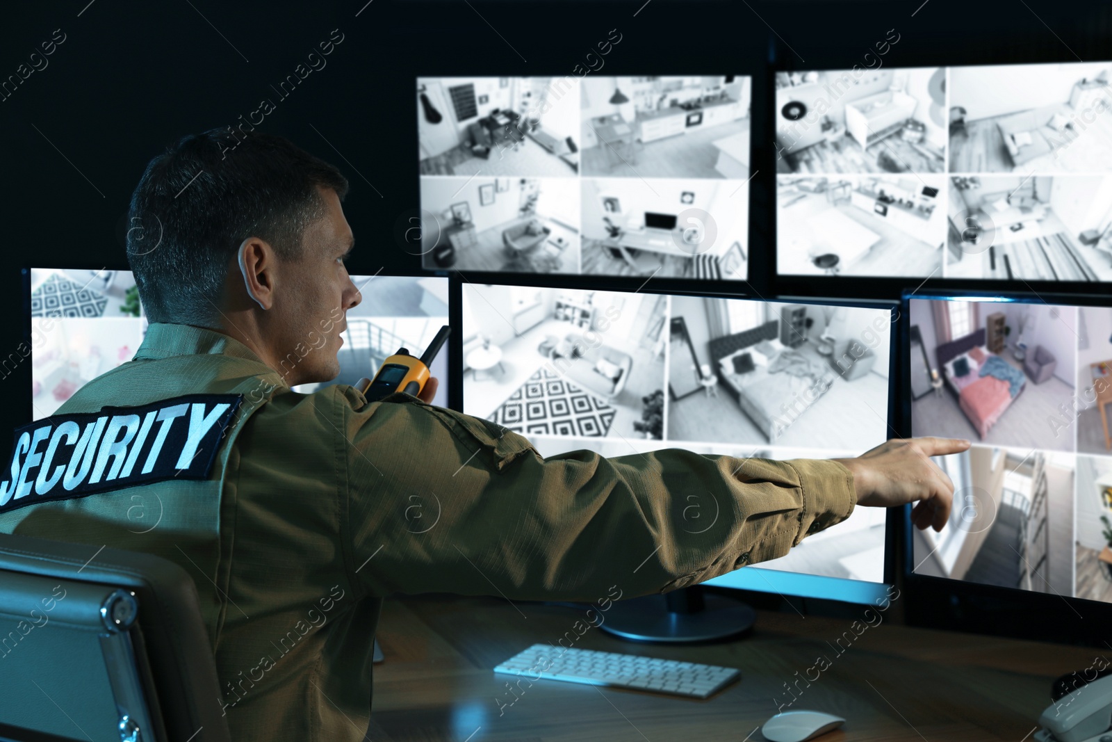 Photo of Security guard with portable transmitter monitoring modern CCTV cameras indoors