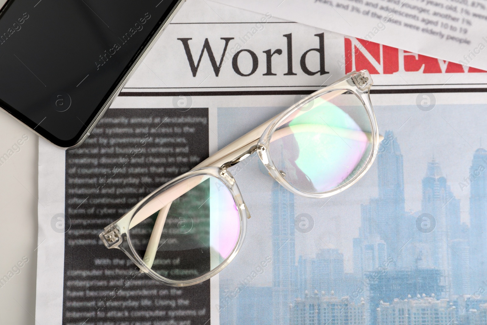 Photo of Glasses and smartphone on newspaper, flat lay