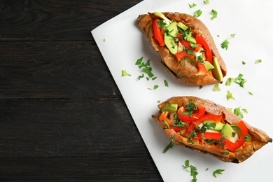 Photo of Top view of stuffed sweet potatoes served on wooden background. Space for text