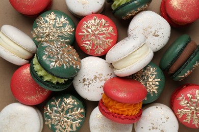 Photo of Beautifully decorated Christmas macarons on brown background, top view