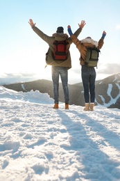 Excited couple with backpacks enjoying mountain view during winter vacation. Space for text