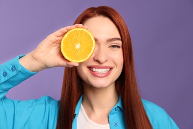 Photo of Redhead woman covering eye with orange on purple background