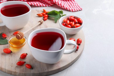 Photo of Fresh rose hip tea and berries on light table