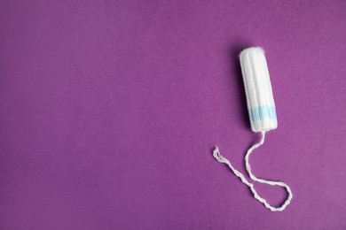 Tampon on purple background, top view. Space for text