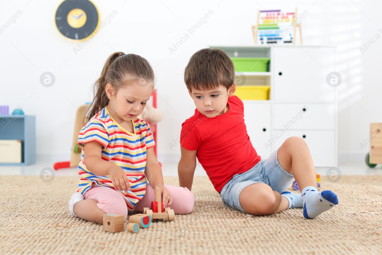 Photo of Cute little children playing with toys on floor at home