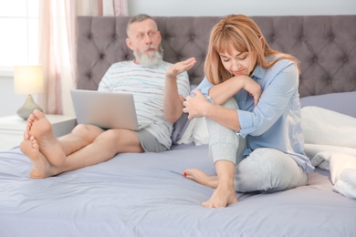 Mature couple with problem in relationship on bed at home