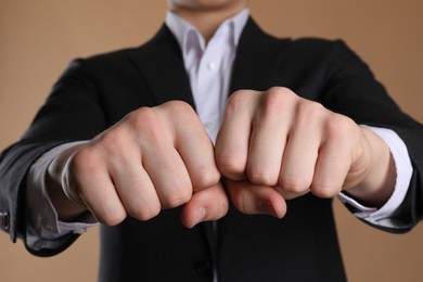 Photo of Businessman showing fists with space for tattoo on beige background, selective focus