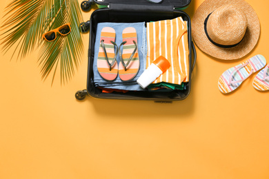 Flat lay composition with open suitcase on orange background