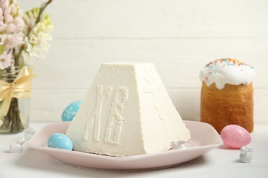 Photo of Traditional cottage cheese Easter paskha and eggs on white wooden table