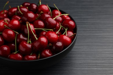 Bowl with ripe sweet cherries on dark wooden table, closeup