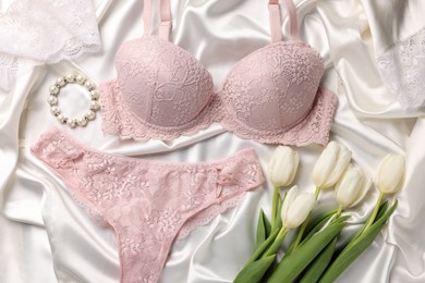 Photo of Flat lay composition with pink women's underwear and tulips on white fabric