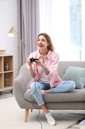 Emotional young woman playing video game at home